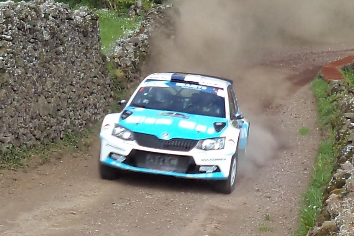 Rally car racing on a narrow dirt road with volcanic stone walls in São Miguel, Azores