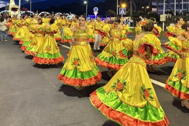 Women in traditional colorful dresses dancing during a street festival in Ponta Delgada São Miguel Azores at dusk