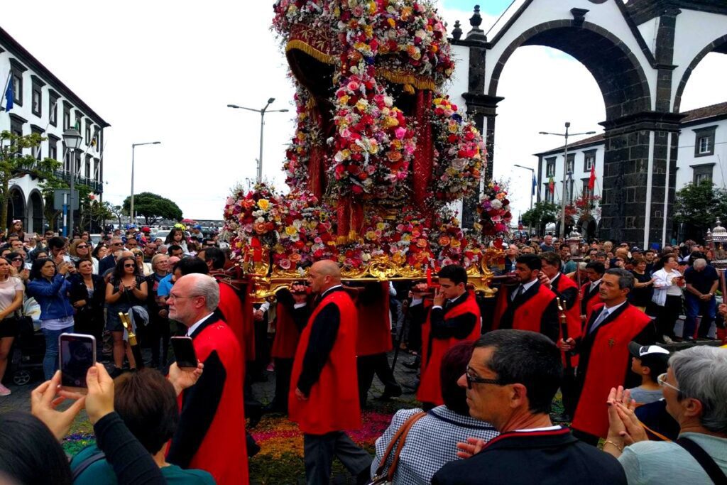 Santo Cristo procession in Ponta Delgada with vibrant floral carriage and red costumes São Miguel Azores